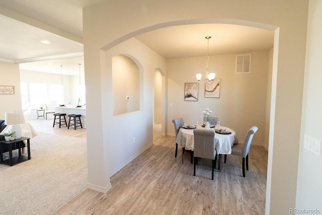 dining area featuring light carpet and an inviting chandelier