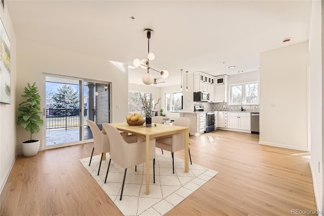 dining area with sink, a wealth of natural light, and light hardwood / wood-style flooring