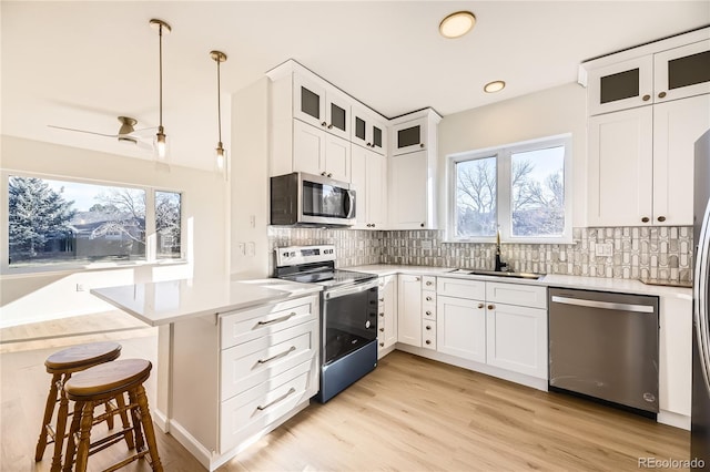 kitchen featuring white cabinetry, pendant lighting, stainless steel appliances, and sink