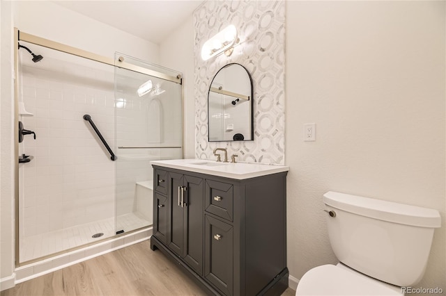 bathroom featuring hardwood / wood-style floors, vanity, toilet, and a shower with shower door