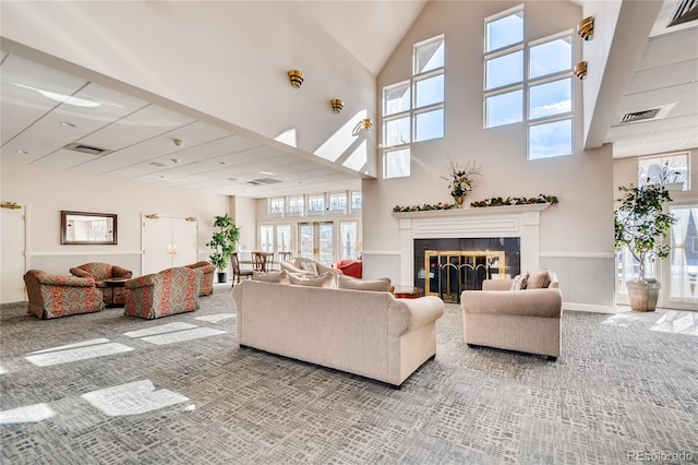 carpeted living room featuring a tile fireplace and a high ceiling