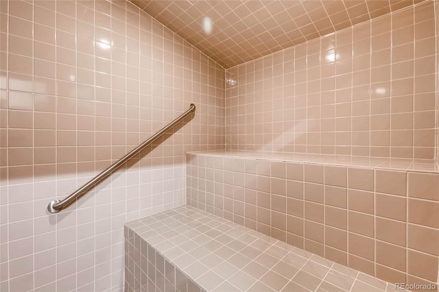 bathroom with a tile shower and lofted ceiling