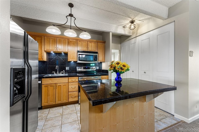 kitchen with a sink, appliances with stainless steel finishes, a center island, a kitchen bar, and decorative light fixtures