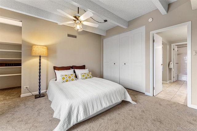 bedroom with beam ceiling, a closet, light colored carpet, visible vents, and a textured ceiling