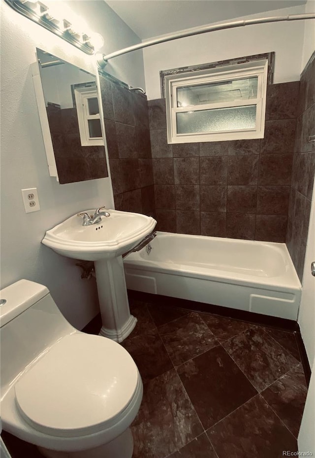 bathroom featuring tiled shower / bath combo and toilet