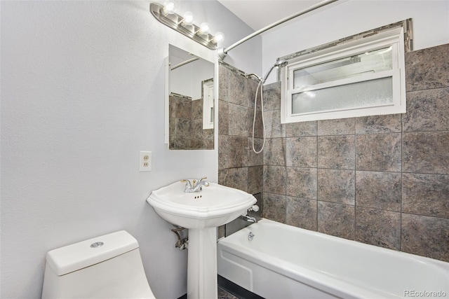 bathroom with toilet and tiled shower / bath combo