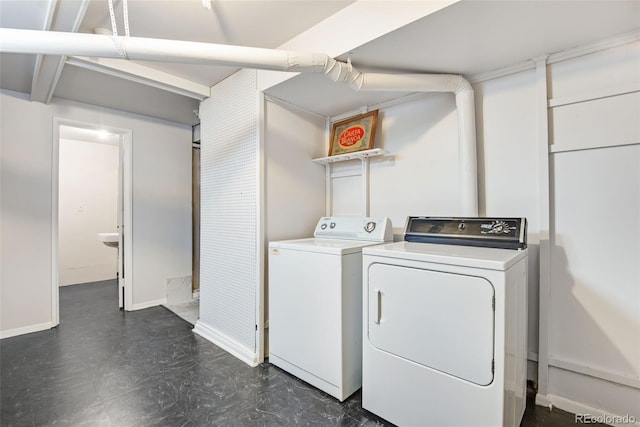 laundry area featuring baseboards, laundry area, separate washer and dryer, and dark floors