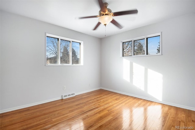 empty room featuring a wealth of natural light, baseboards, and visible vents