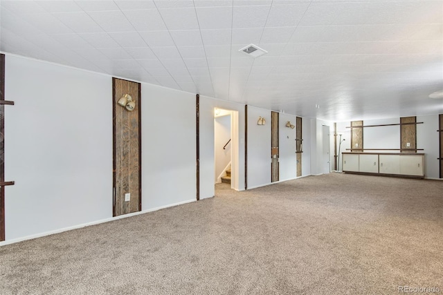 interior space with carpet flooring, visible vents, baseboards, and stairway