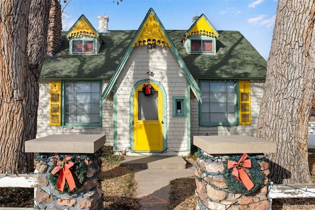 view of front of house with roof with shingles and a chimney