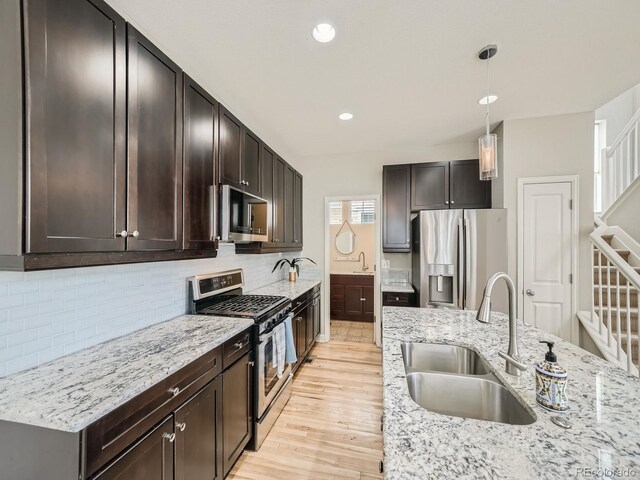 kitchen with tasteful backsplash, stainless steel appliances, dark brown cabinets, light hardwood / wood-style flooring, and sink