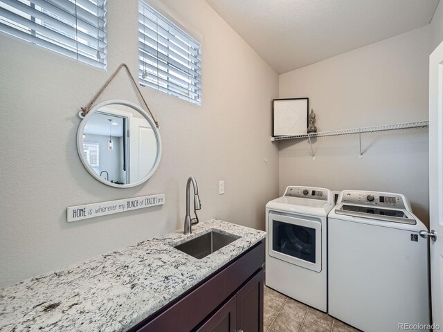 clothes washing area featuring cabinets, a wealth of natural light, washer and dryer, and sink