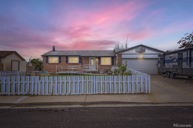 ranch-style home with an attached garage, a fenced front yard, concrete driveway, and brick siding