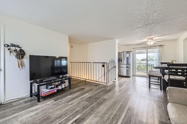 living room featuring wood finished floors, a textured ceiling, and ceiling fan
