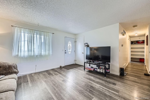 living area with a textured ceiling, wood finished floors, and baseboards
