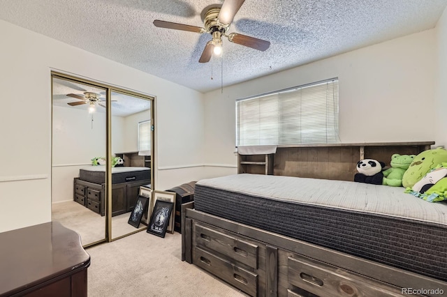 bedroom with light colored carpet, a textured ceiling, a ceiling fan, and a closet