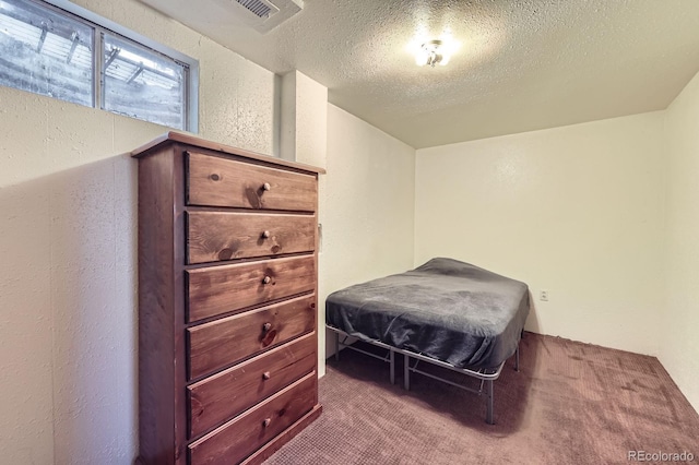 carpeted bedroom featuring a textured ceiling and a textured wall