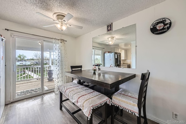 dining space featuring a ceiling fan, a textured ceiling, and light wood-type flooring