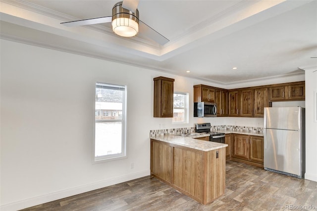 kitchen with ceiling fan, kitchen peninsula, crown molding, light hardwood / wood-style floors, and appliances with stainless steel finishes