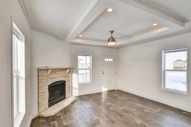 unfurnished living room with wood-type flooring, a tray ceiling, ceiling fan, and ornamental molding