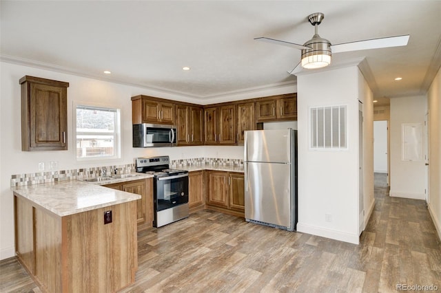 kitchen with sink, tasteful backsplash, kitchen peninsula, appliances with stainless steel finishes, and ornamental molding