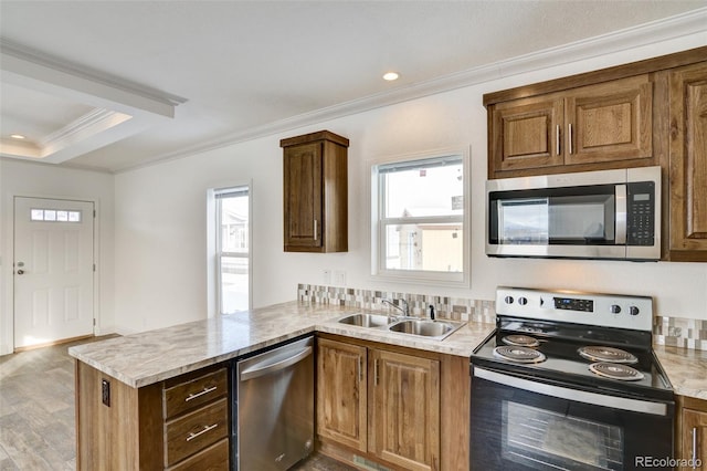 kitchen with kitchen peninsula, sink, ornamental molding, and appliances with stainless steel finishes