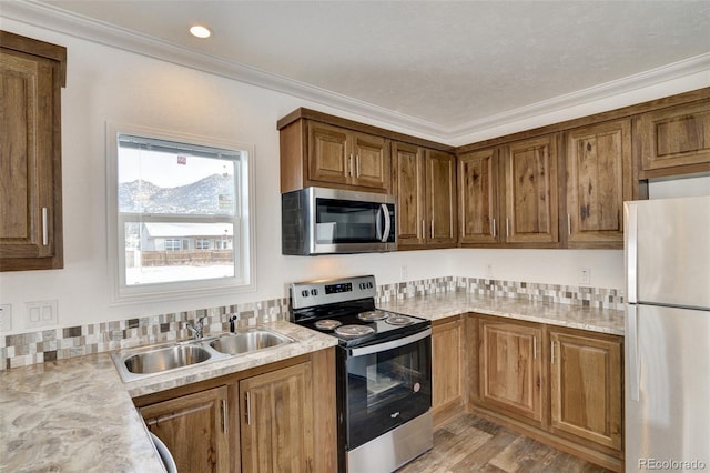 kitchen featuring appliances with stainless steel finishes, light hardwood / wood-style floors, crown molding, and sink