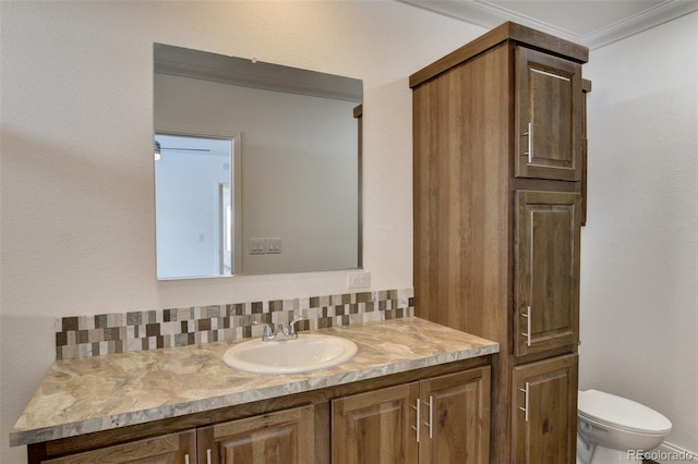 bathroom featuring backsplash, toilet, vanity, and ornamental molding