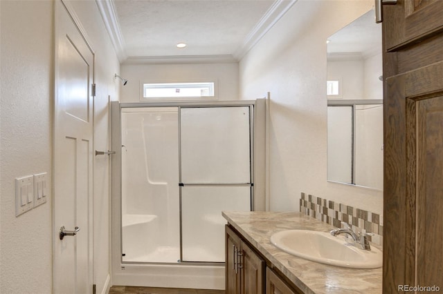 bathroom featuring a shower with shower door, ornamental molding, vanity, and tasteful backsplash