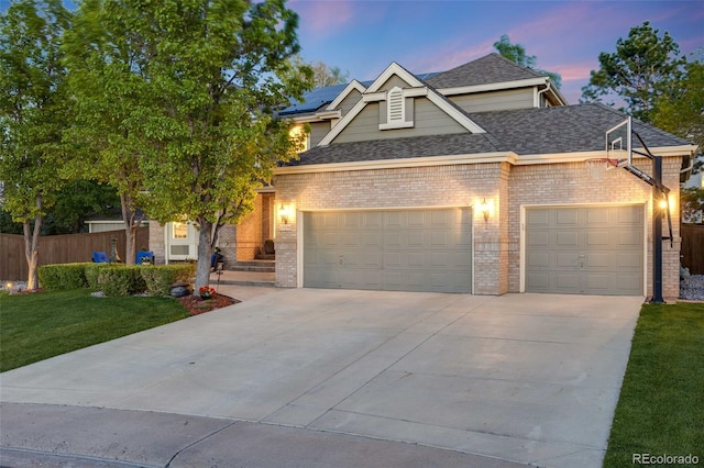 view of front of home with an attached garage, driveway, brick siding, solar panels, and roof with shingles