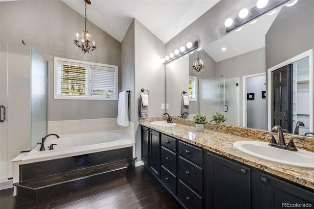 full bath featuring vaulted ceiling, a chandelier, a stall shower, a garden tub, and double vanity