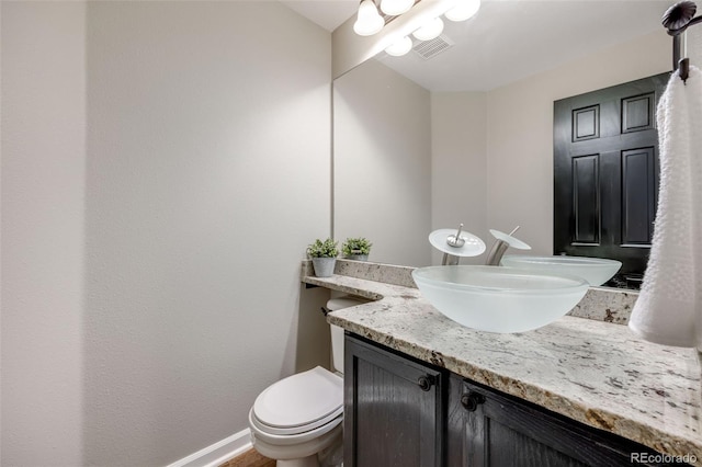 bathroom with vanity, toilet, and baseboards