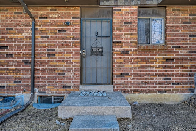 view of exterior entry featuring brick siding