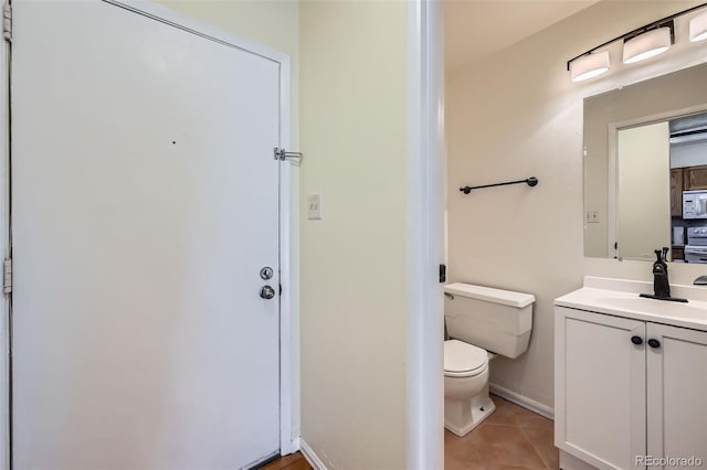 bathroom with toilet, vanity, baseboards, and tile patterned floors