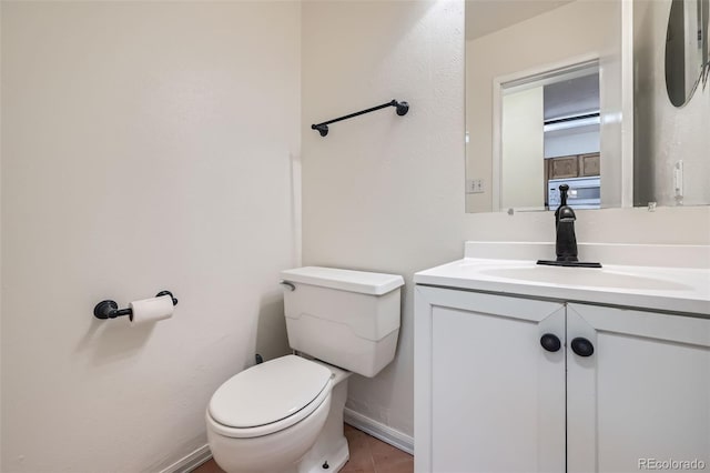 half bathroom with toilet, baseboards, and vanity