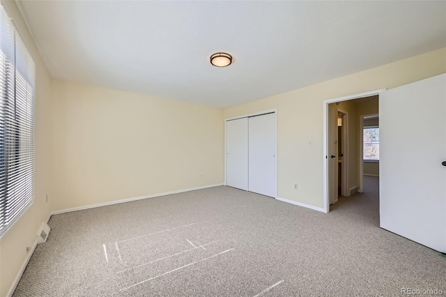 unfurnished bedroom featuring a closet, light carpet, and baseboards