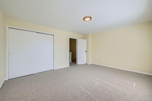 unfurnished bedroom featuring carpet floors, baseboards, and a closet