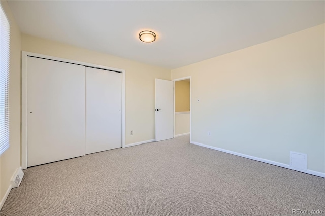 unfurnished bedroom with visible vents, a closet, baseboards, and carpet flooring