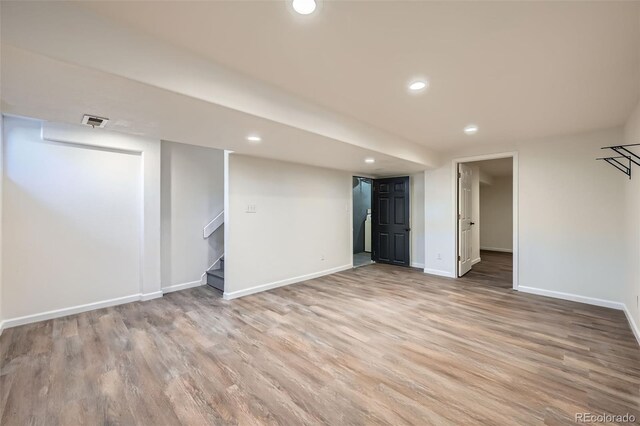 finished basement with baseboards, stairway, visible vents, and light wood-style floors