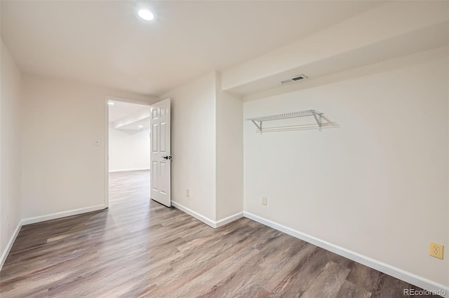 empty room featuring recessed lighting, wood finished floors, visible vents, and baseboards