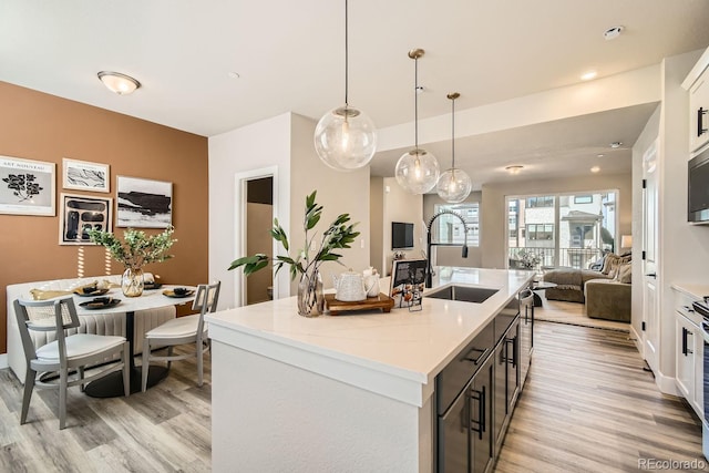 kitchen with sink, pendant lighting, white cabinetry, and a kitchen island with sink