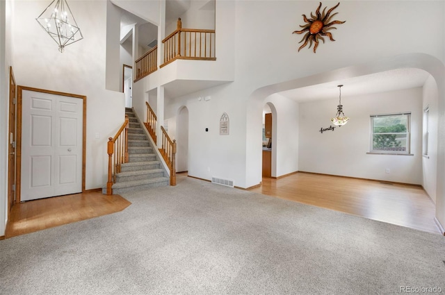 2859 Front Royal Dr, Colorado Springs, CO 80919 - unfurnished living room with carpet flooring, arched walkways, stairs, a towering ceiling, and wood finished floors