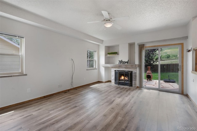 2859 Front Royal Dr, Colorado Springs, CO 80919 - unfurnished living room with wood finished floors, a textured ceiling, a warm lit fireplace, plenty of natural light, and ceiling fan