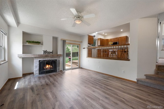 2859 Front Royal Dr, Colorado Springs, CO 80919 - unfurnished living room with a textured ceiling, wood finished floors, a brick fireplace, stairway, and ceiling fan