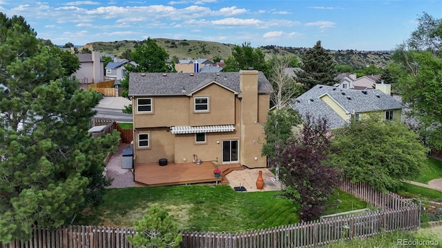 2859 Front Royal Dr, Colorado Springs, CO 80919 - rear view of property with stucco siding, a wooden deck, a fenced backyard, a chimney, and a residential view