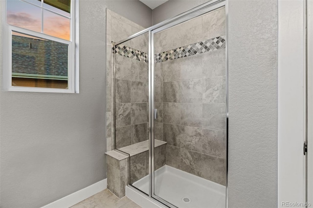 bathroom featuring a stall shower, baseboards, and a textured wall