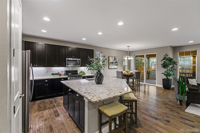 kitchen featuring appliances with stainless steel finishes, dark wood-style flooring, a breakfast bar, and dark cabinets