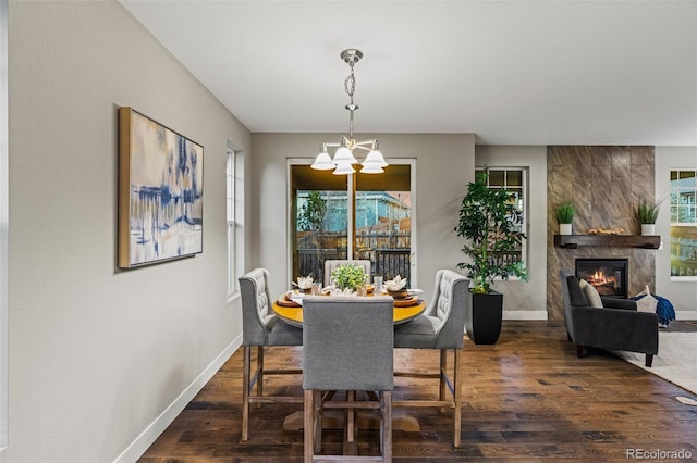 dining space featuring a chandelier, dark wood-type flooring, a fireplace, and baseboards