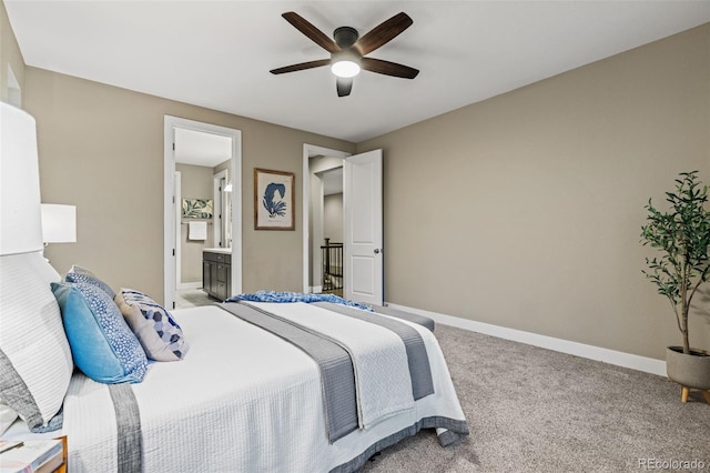 bedroom featuring light colored carpet, ceiling fan, ensuite bath, and baseboards