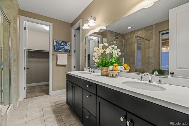 bathroom with double vanity, a shower stall, a spacious closet, and a sink